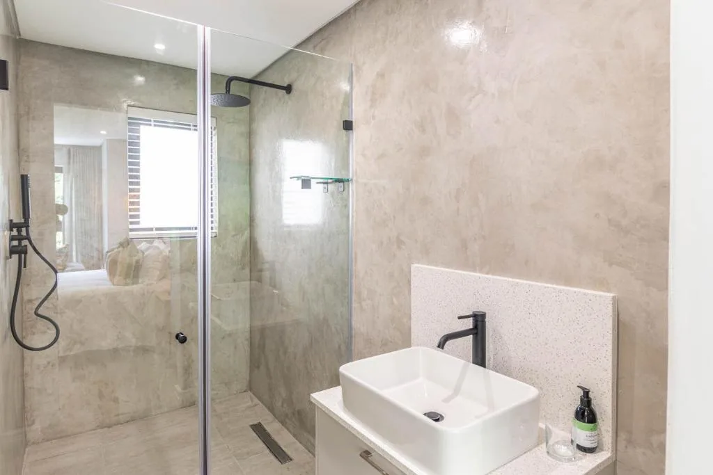 Modern bathroom with walk-in shower, white vessel sink, and neutral tile finishes