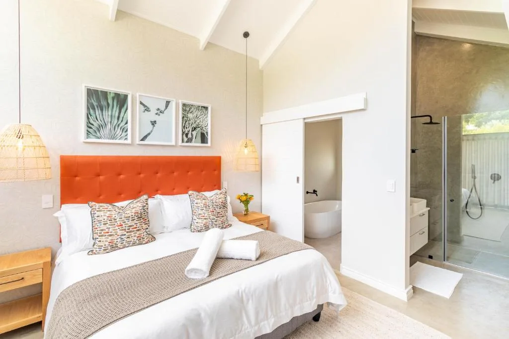 Modern bedroom with orange headboard, white bedding, ensuite bathroom visible