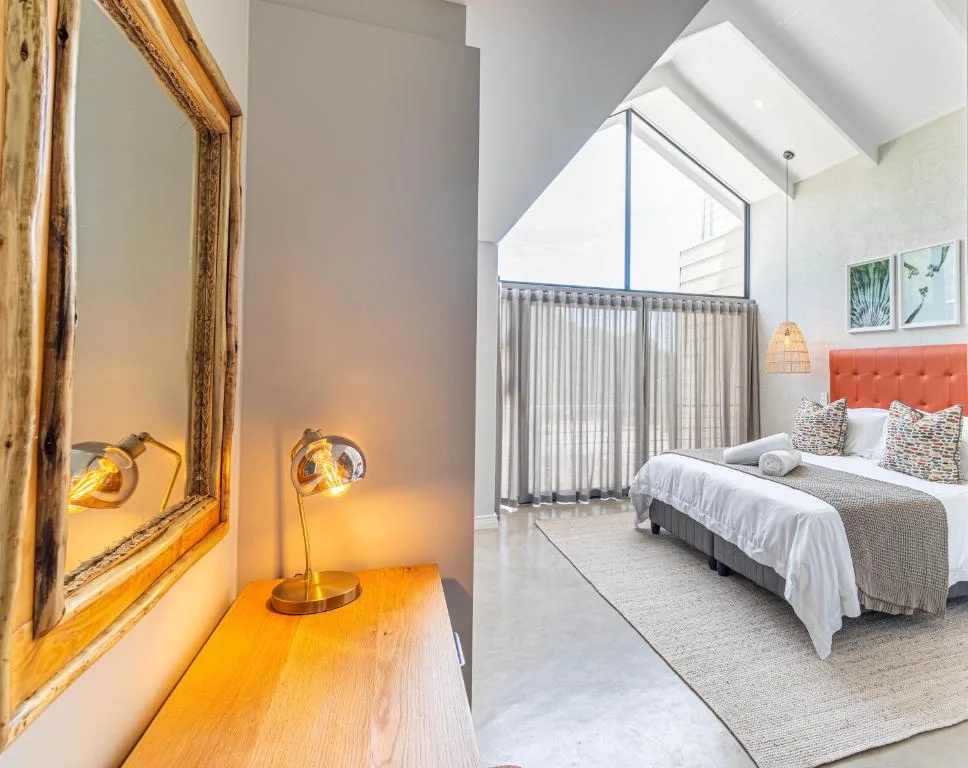 Modern bedroom with queen bed, orange headboard, skylights, and wooden desk