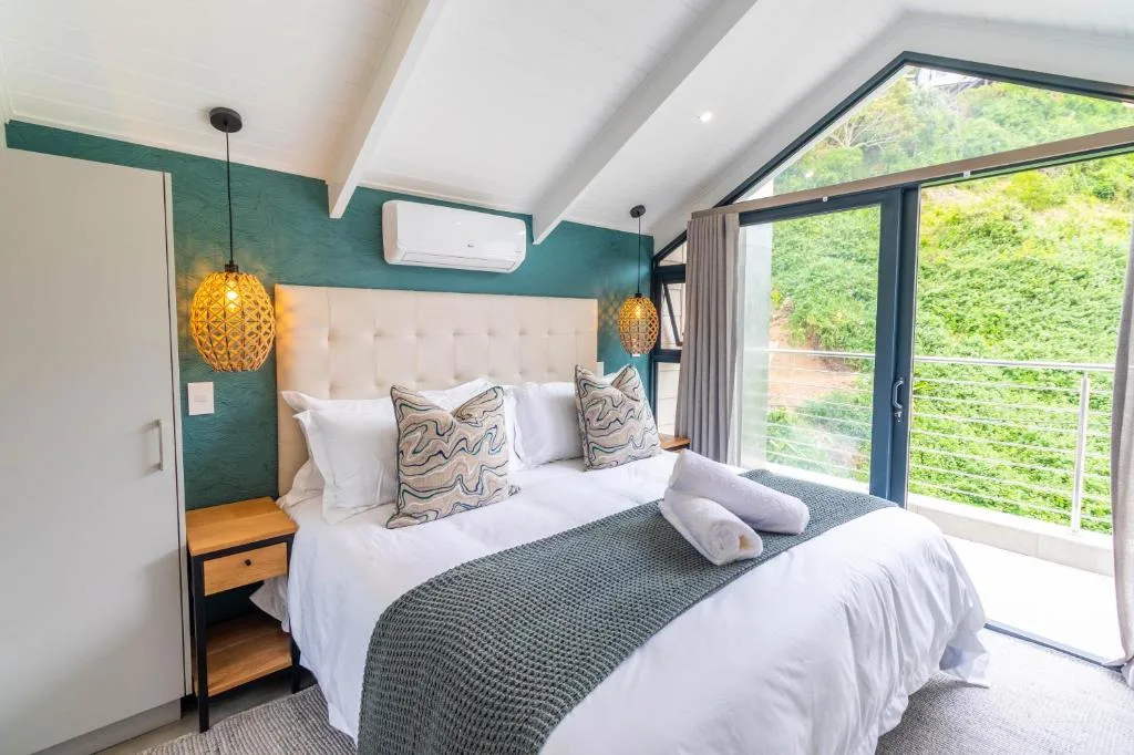 Modern bedroom with teal accent wall, pendant lights, and garden views