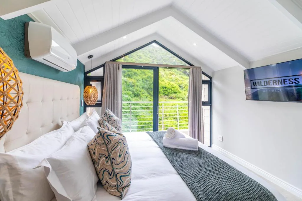 Modern bedroom with white bed, mountain views through large glass doors