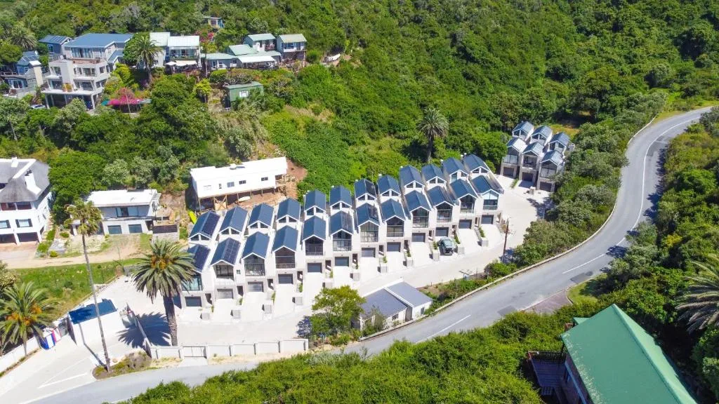 Aerial view of modern white apartment complex nestled among green hillside vegetation