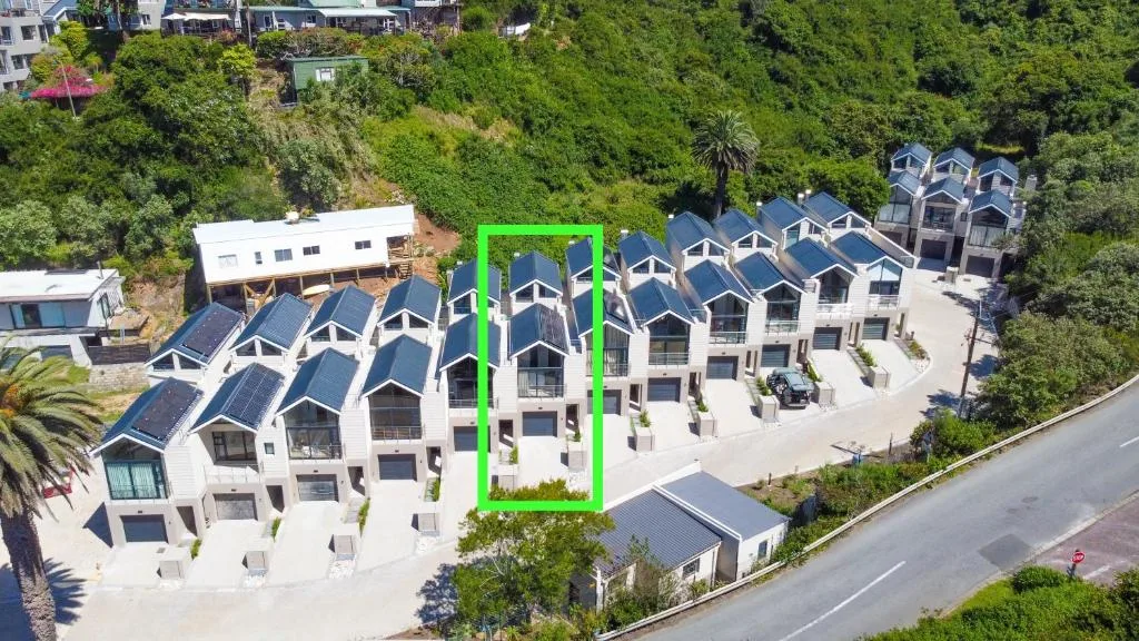 Aerial view of white modern townhouses with solar panels nestled in green hillside