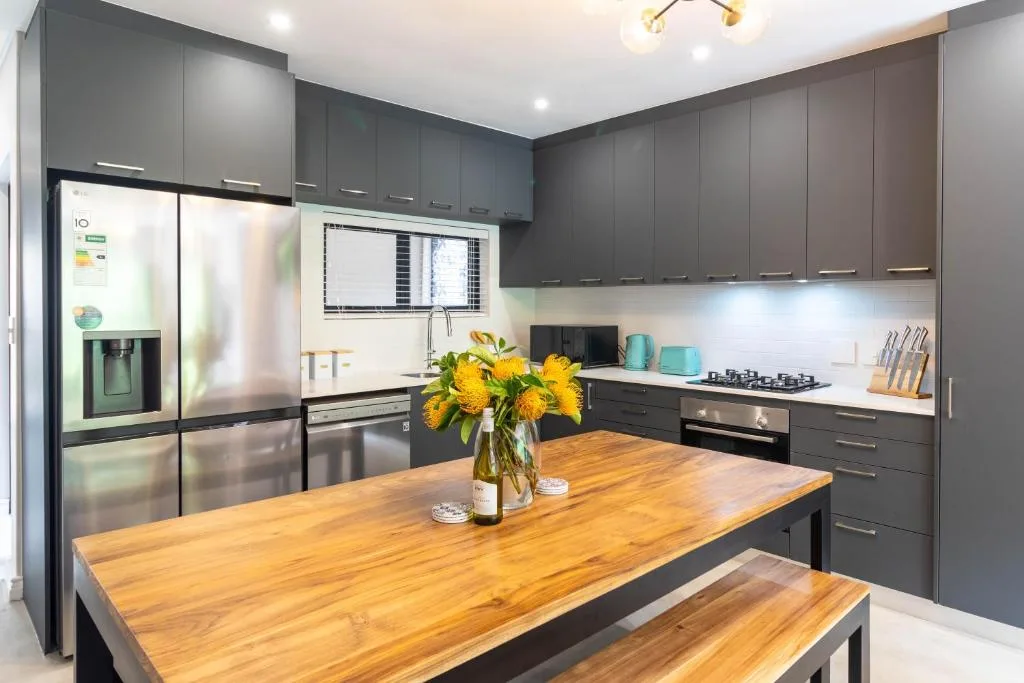Modern kitchen with dark cabinetry, stainless steel appliances, wooden island countertop