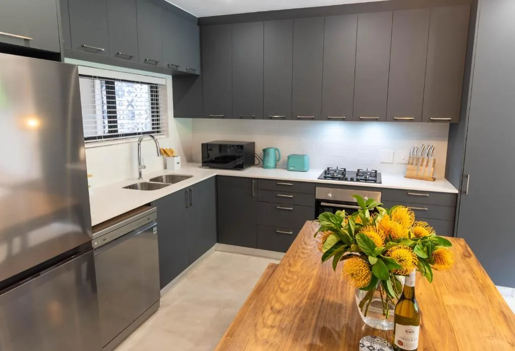 Modern kitchen with dark cabinetry, stainless steel appliances, and wooden island
