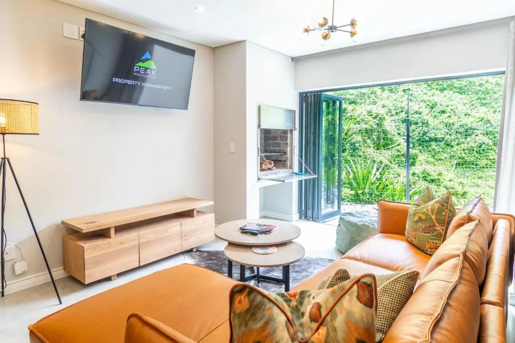 Modern lounge with orange leather sofa, TV, and garden views through bifold doors