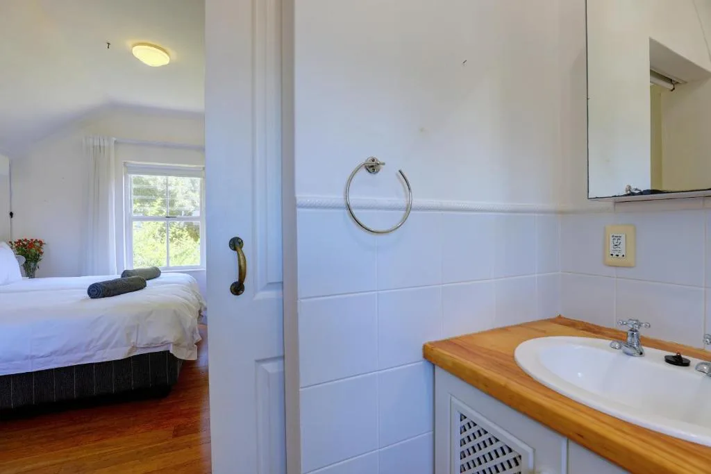 Ensuite bathroom with white tiles, wooden vanity, and window view