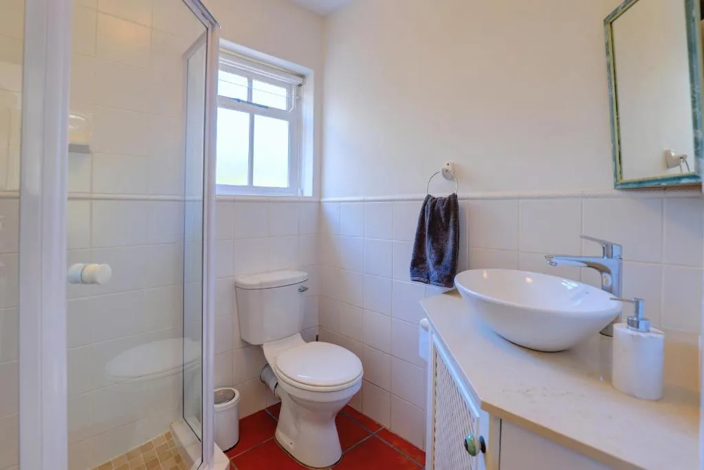 Clean bathroom with toilet, round vessel sink, and glass shower enclosure