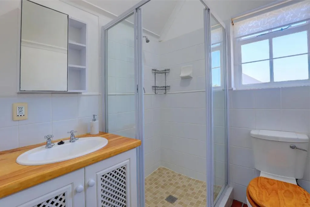 Clean bathroom with wooden vanity, white sink, and enclosed shower stall