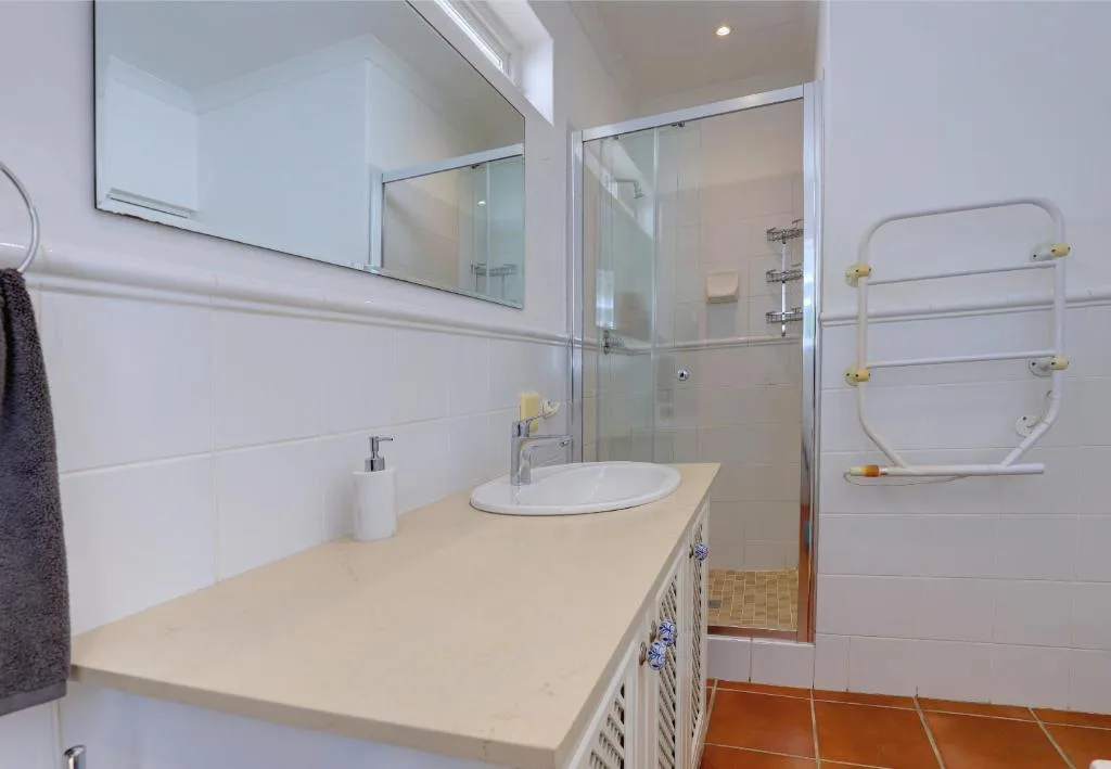 Modern bathroom with vanity sink, large mirror, and enclosed shower cubicle