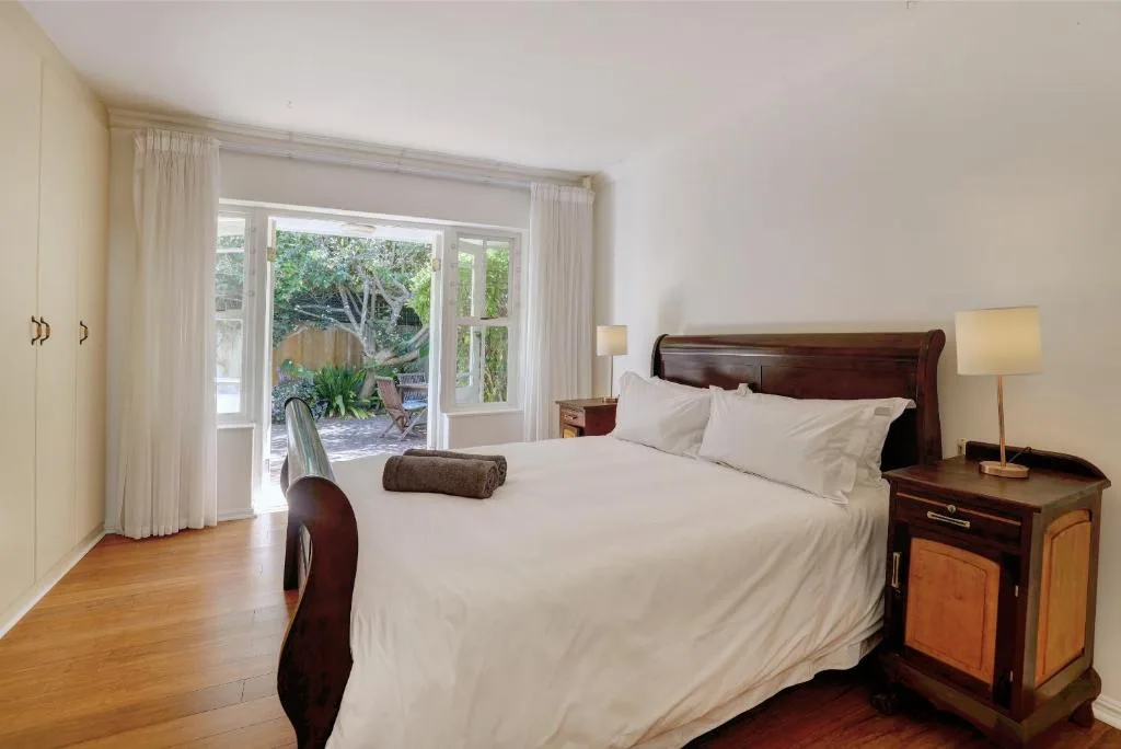 Spacious bedroom with queen bed, wooden nightstand, garden doors overlooking patio