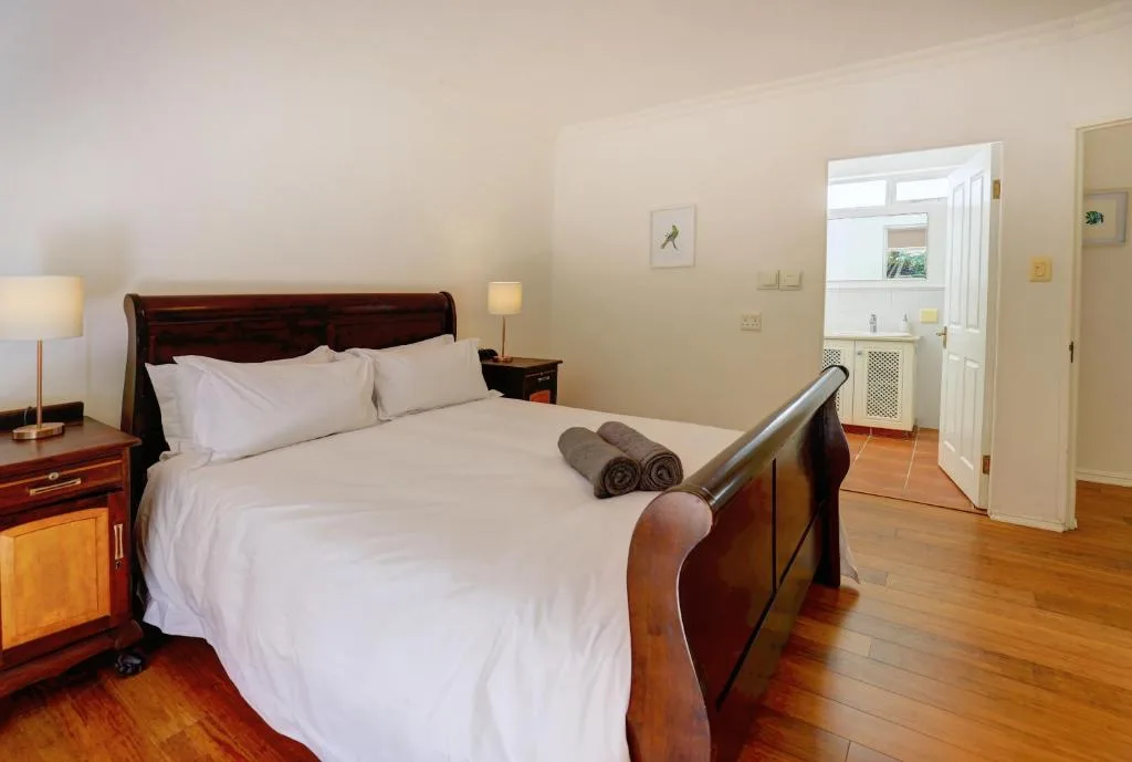 Spacious bedroom with wooden bed frame and white linens, wooden flooring