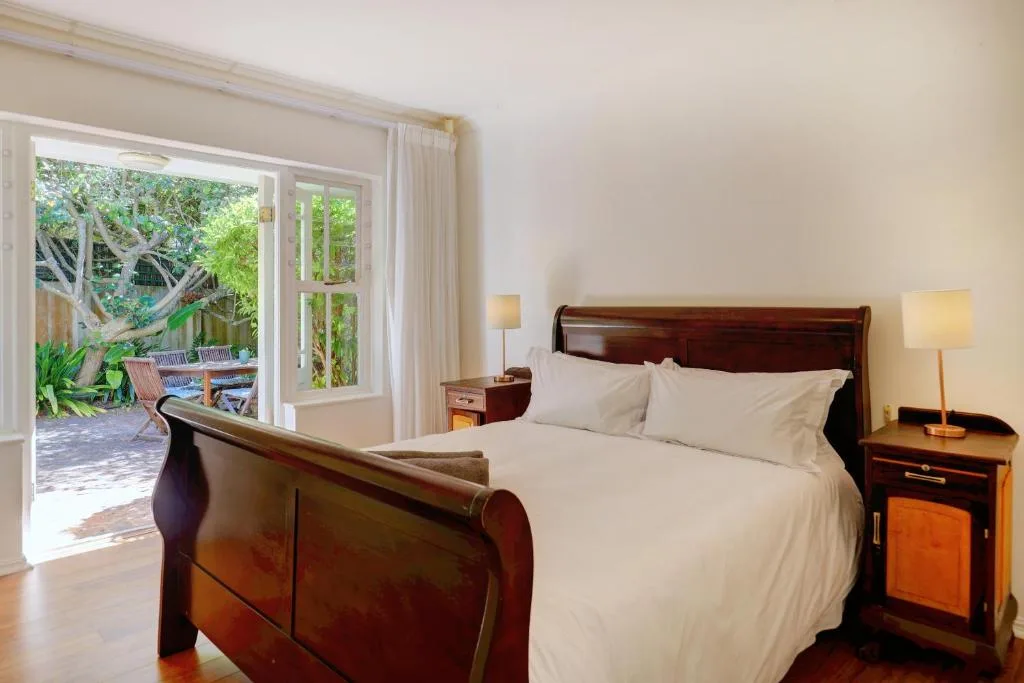 Spacious bedroom with wooden sleigh bed and garden view through French doors