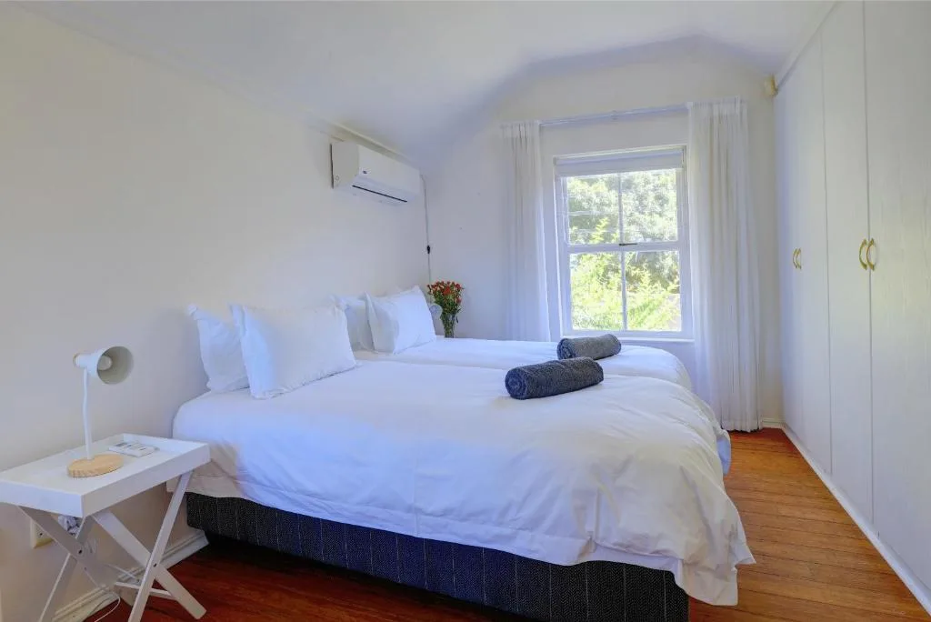 Bright bedroom with queen bed, white linens, large window, wooden floors