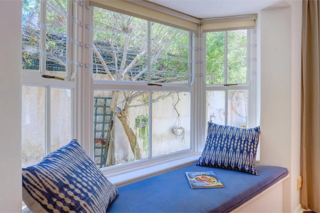 Cozy window seat with blue cushions and patterned pillows overlooking garden trees