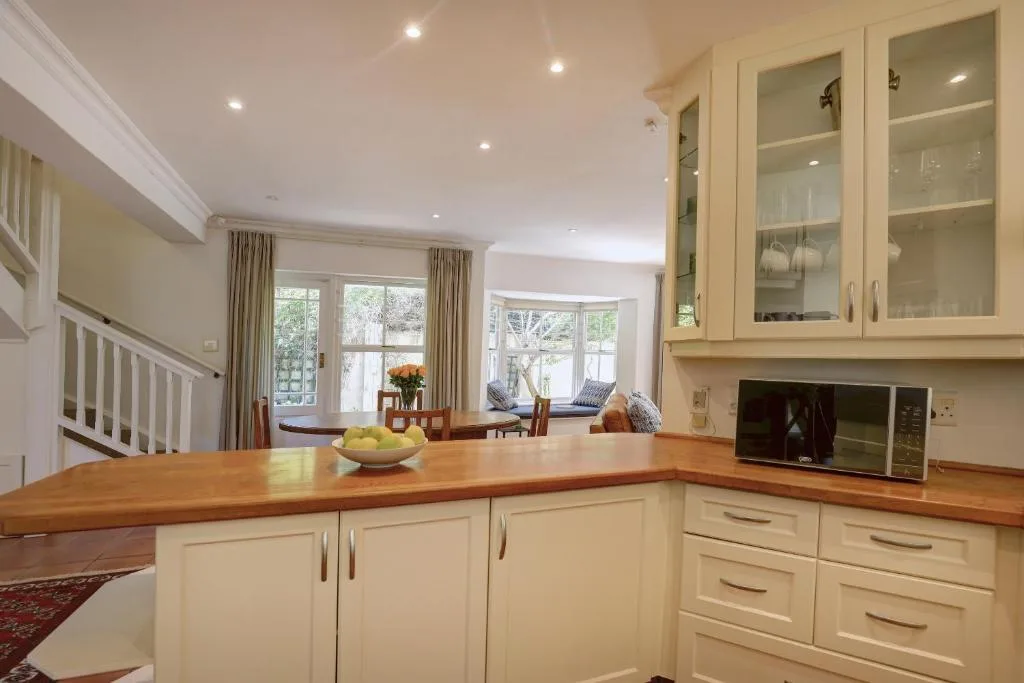 Modern cream kitchen with wooden counters and large windows overlooking gardens