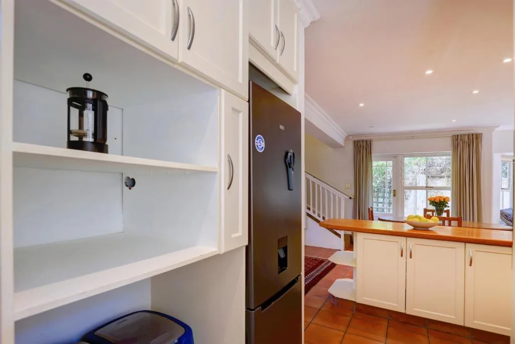 Modern white kitchen with refrigerator, open shelving, and wood countertop
