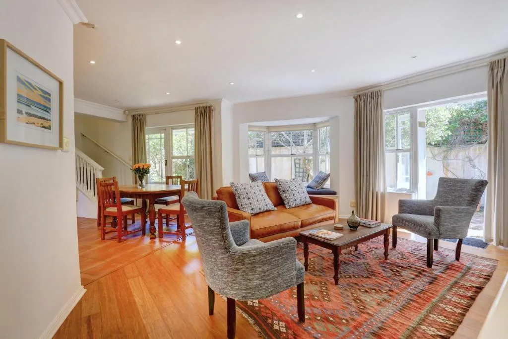 Bright living room with orange sofa, gray armchairs, wooden coffee table