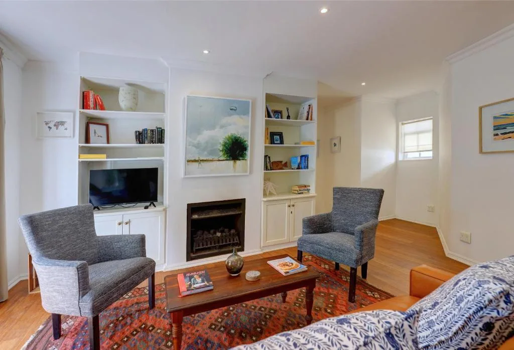 Modern lounge with armchairs, fireplace, TV, and built-in shelving