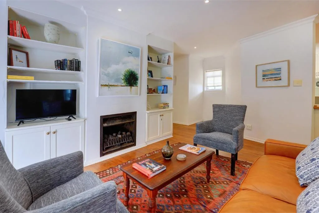 Bright lounge with fireplace, TV, comfortable seating, and coastal artwork