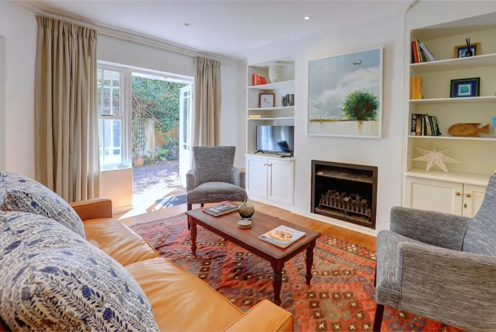 Bright living room with fireplace, comfortable seating, and garden access doors