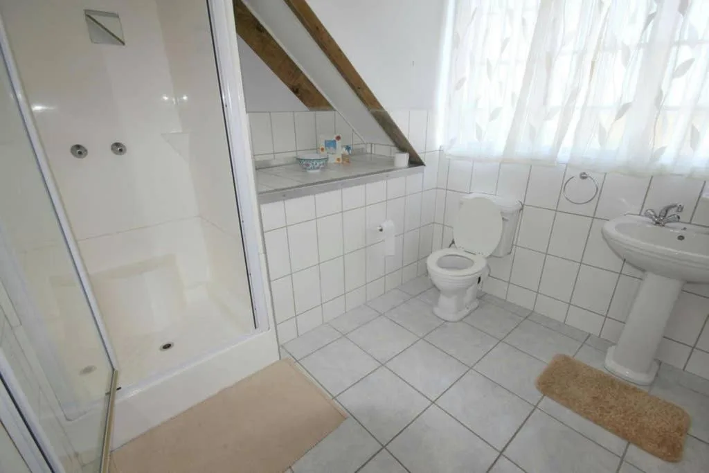 Clean white bathroom with shower enclosure, toilet, pedestal sink, and vanity