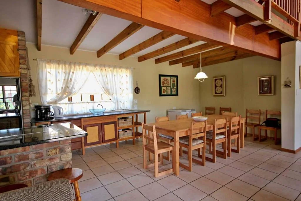Open-plan dining area with wooden table and chairs, exposed beams overhead