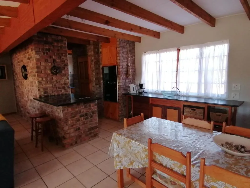 Open-plan dining and kitchen area with wooden beams and brick fireplace