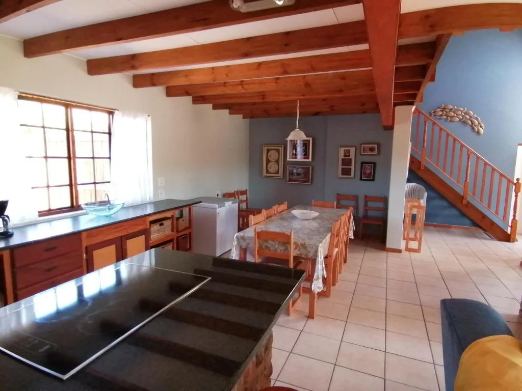 Open-plan dining area with wooden beams and table set for guests