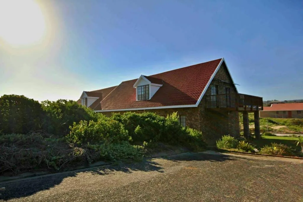 Modern stone cottage with red roof and dormer windows in rural setting