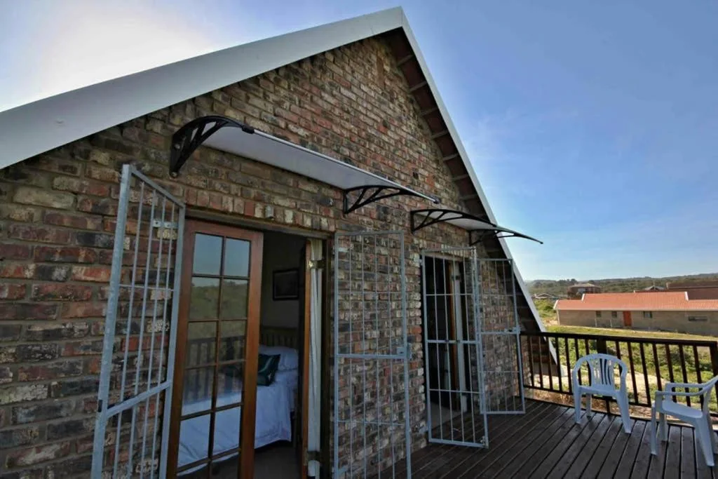 Brick cottage entrance with wooden deck and countryside views beyond