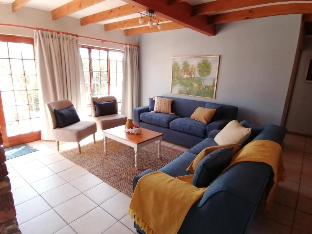 Spacious lounge with blue sofas, accent chairs, and wooden beam ceiling