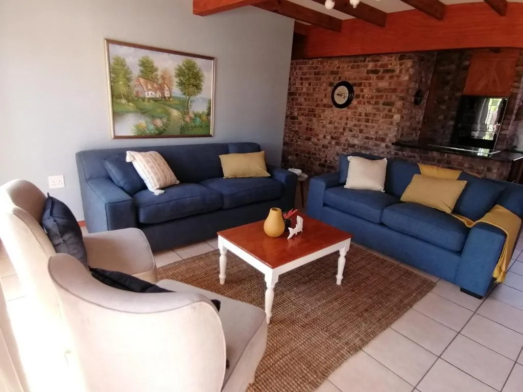 Spacious lounge with blue sofas, cream armchair, and red coffee table