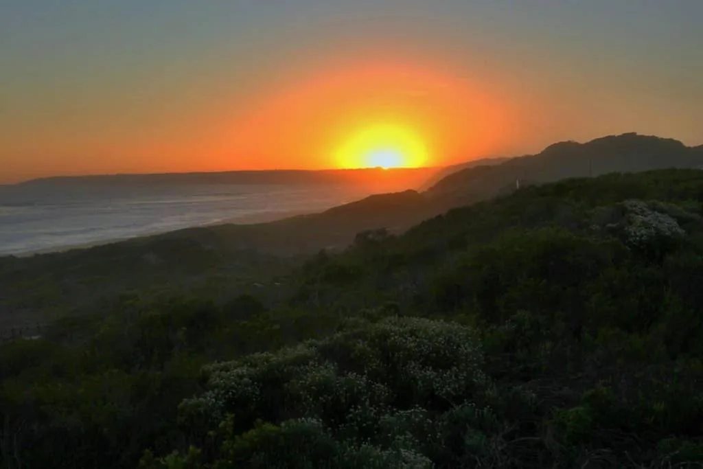 Golden sunset over ocean and mountains from property vantage point