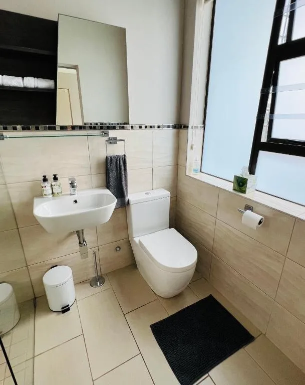 Modern bathroom with round sink, toilet, and decorative tile border