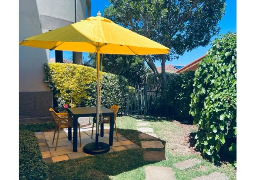 Shaded patio area with yellow umbrella and outdoor seating in garden