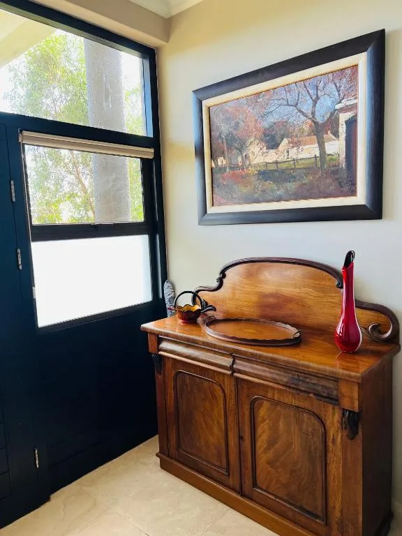 Wooden dresser with red vase and framed artwork in entry area
