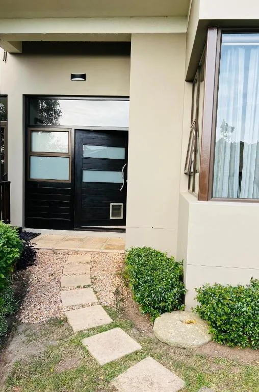 Modern cream and black entrance with manicured hedges and stone pathway