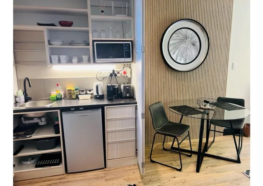 Modern kitchenette with white cabinetry, microwave, and compact dining area