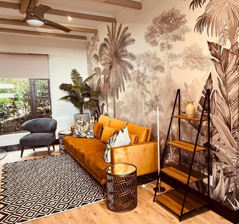 Stylish living room with orange leather sofa and tropical botanical wallpaper