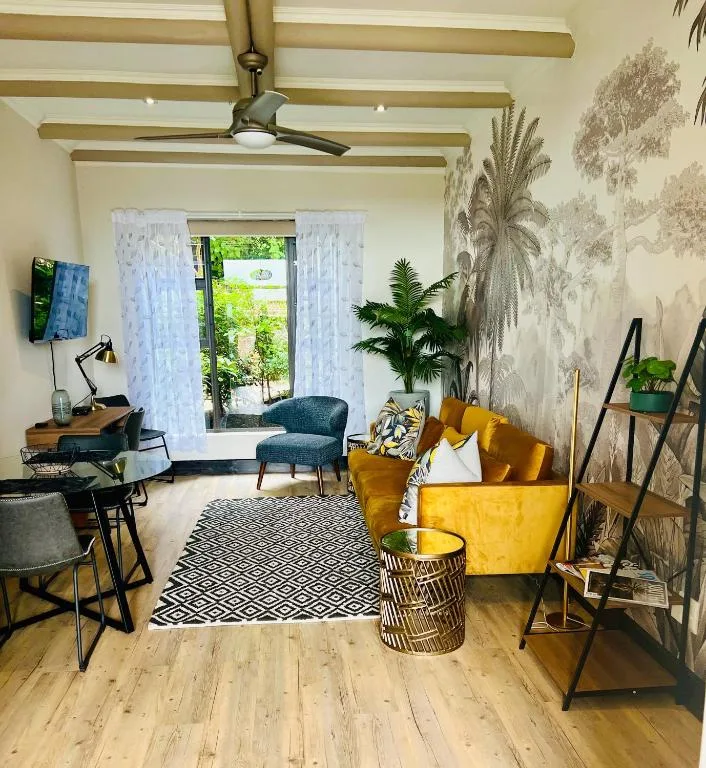 Bright living room with yellow sofa, exposed beams, and garden views through patio doors
