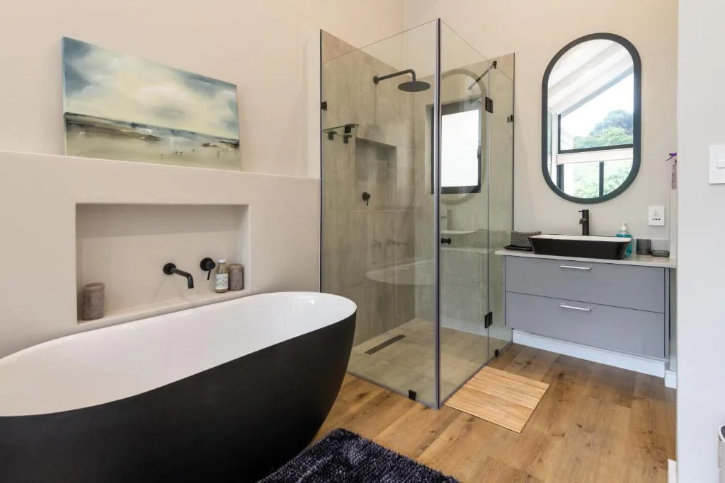 Modern bathroom with black freestanding tub, walk-in shower, and vanity
