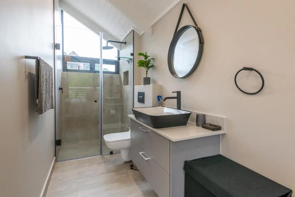 Modern bathroom with black vessel sink, glass shower enclosure, toilet