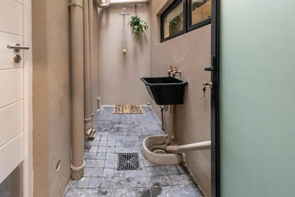 Narrow bathroom with black sink, toilet, and tiled flooring