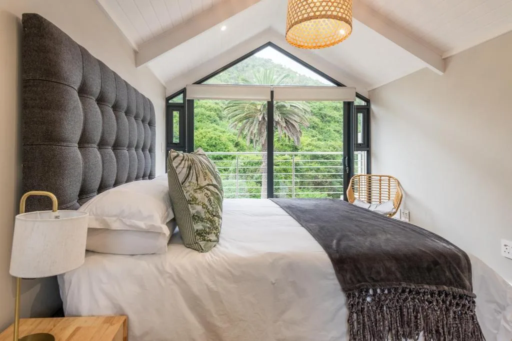Modern bedroom with tufted headboard and views of lush gardens