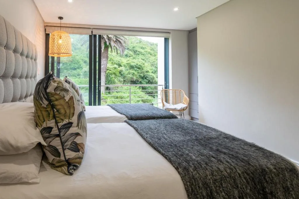 Modern bedroom with twin beds overlooking lush green forest views