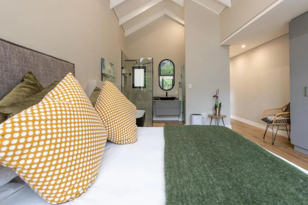 Spacious bedroom with yellow patterned pillows and ensuite bathroom visible