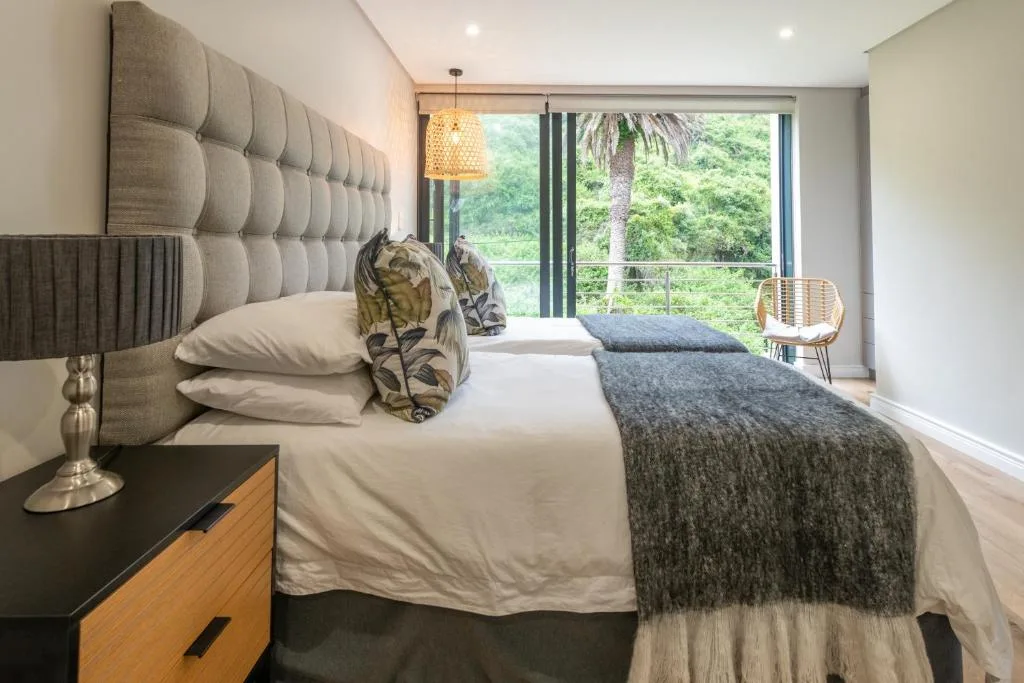 Modern bedroom with upholstered headboard and garden view through large sliding doors