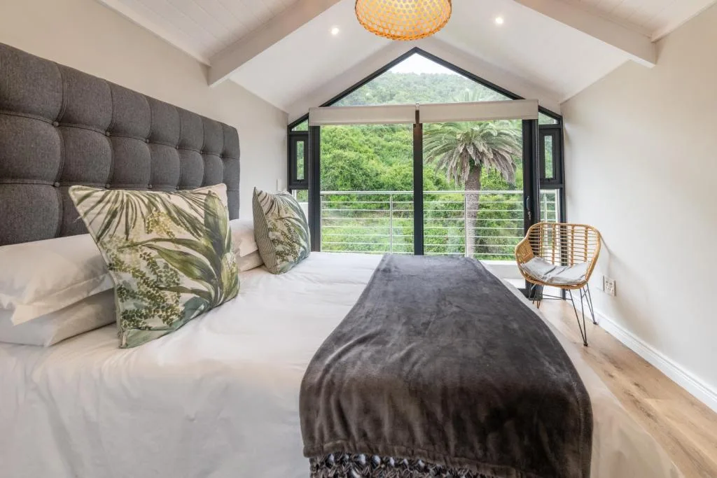 Spacious bedroom with garden views through large glass doors and vaulted ceiling