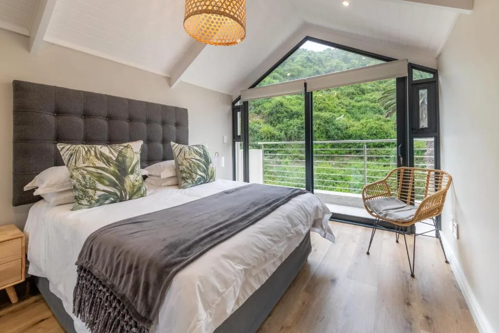 Modern bedroom with forest views through floor-to-ceiling sliding doors